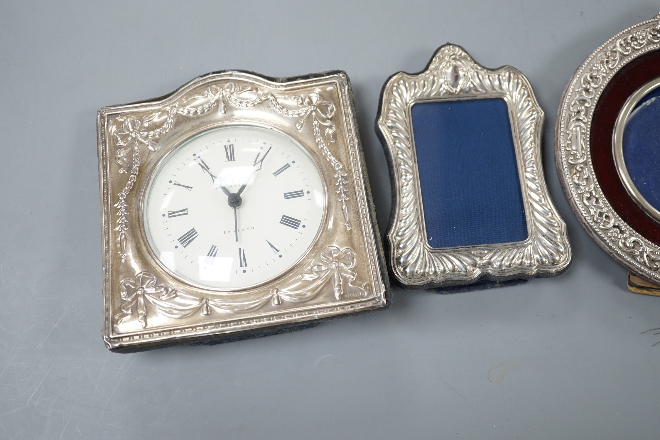 A modern silver mounted desk timepiece, 15.2cm and two mounted photograph frames, including Italian 925 and Edwardian repousse.